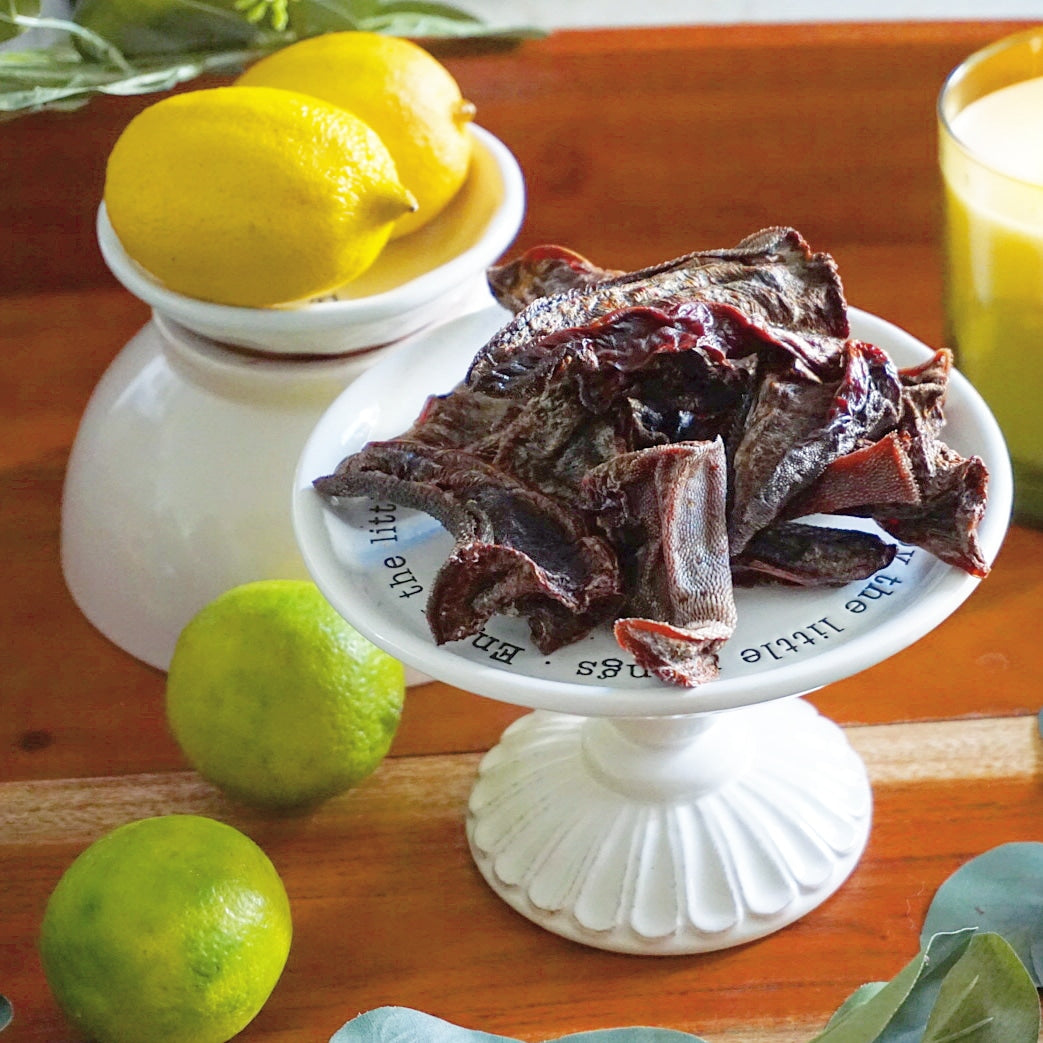 Dried fruit on a white stand with lemons and limes on a wooden surface